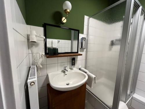 a bathroom with a sink and a shower with a mirror at Südstadt-Hotel Wilhelmshaven in Wilhelmshaven
