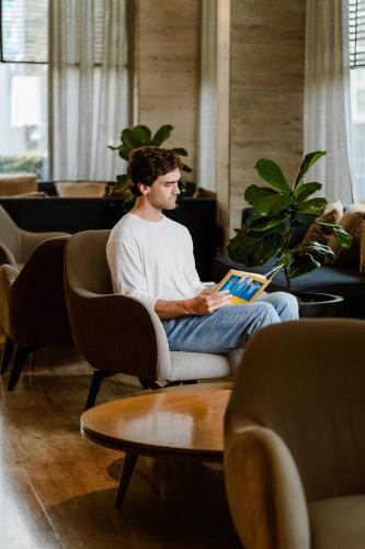a man sitting in a chair reading a book at Pullman Vina del Mar San Martin in Viña del Mar