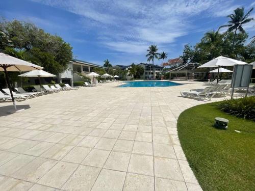 a swimming pool with chairs and umbrellas in a resort at Amazing beach and golf condo Playa Dorada in Sampiño