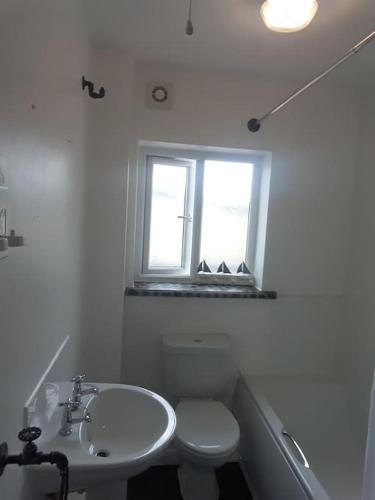 a bathroom with a sink and a toilet and a window at Cute Flat 600m to the beach private parking in Perranporth