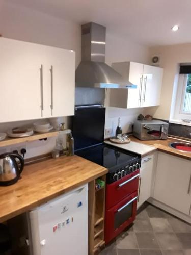 a kitchen with white cabinets and a red stove top oven at Cute Flat 600m to the beach private parking in Perranporth