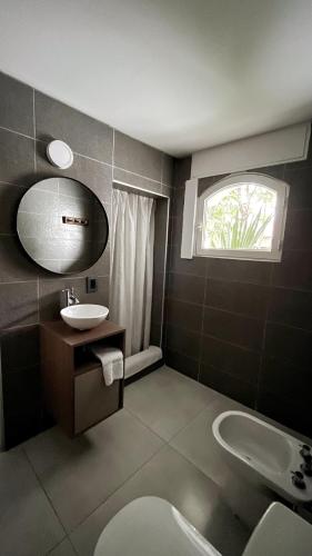 a bathroom with a sink and a toilet and a window at Arístides Lodge in Mendoza