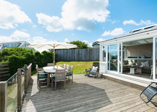 a deck with a table and chairs and an umbrella at Atlantis in Polzeath