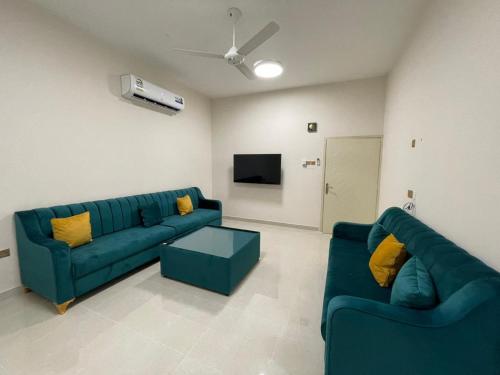 a living room with two blue couches and a tv at شقق مفروشة صلالة - Furnished Apartments Salalah in Salalah