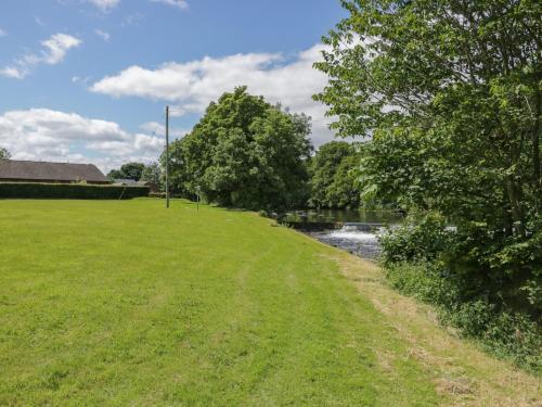 a grassy field next to a river at 1 Eamont Park in Penrith