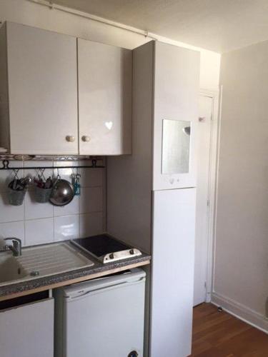 une cuisine avec des armoires blanches et un réfrigérateur blanc dans l'établissement Paris top location, à Paris