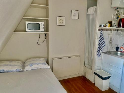 Cette petite chambre comprend un lit et un four micro-ondes. dans l'établissement Paris top location, à Paris