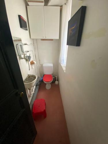 Elle comprend une petite salle de bains pourvue de toilettes et d'un tabouret rouge. dans l'établissement Paris top location, à Paris