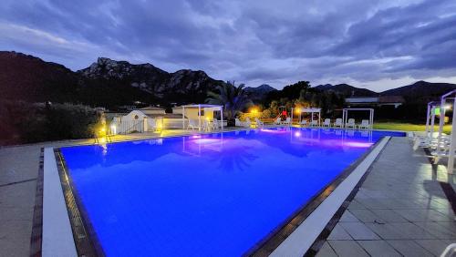 a large blue swimming pool with mountains in the background at Hotel Cardedu in Cardedu