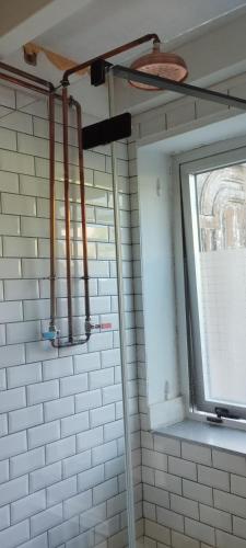 a bathroom with a window and a white tiled wall at A Cascada do Ézaro in Dumbría