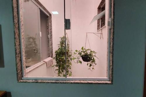 a mirror on a wall with a plant in a window at 50m da praia de Itaipava, 8km Piúma, 15 km Iriri in Itapemirim