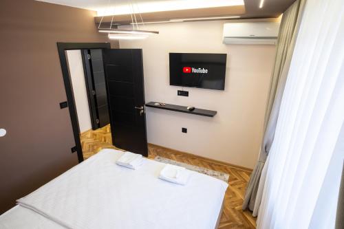 a room with a bed and a tv on the wall at Trpeza Luxury Apartments, free parking in Niš
