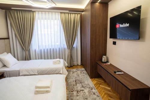 a hotel room with two beds and a flat screen tv at Trpeza Luxury Apartments, free parking in Niš