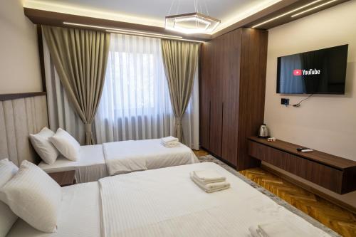 a hotel room with two beds and a flat screen tv at Trpeza Luxury Apartments, free parking in Niš