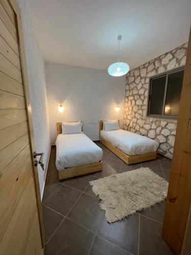 two beds in a room with a door and a rug at Le Réel Kaouki in Sidi Kaouki