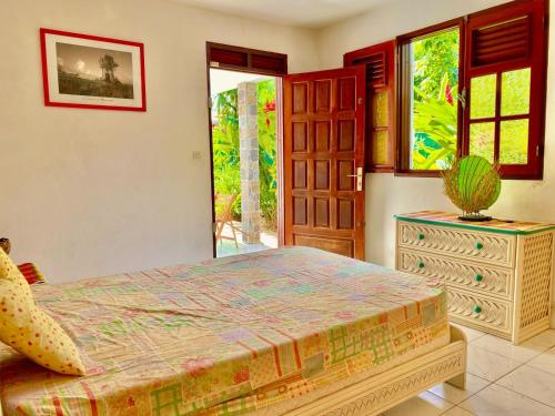 Un dormitorio con una cama, una cómoda y ventanas. en Résidence Les Ziottines, en Deshaies