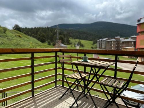 a table and two chairs on a balcony with a view at Apartamento DALIA in La Molina