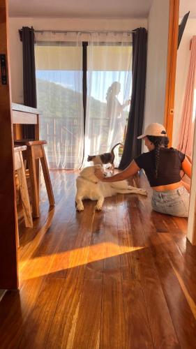 a woman sitting on the floor with a dog at Bungalows Paraíso Celeste in Bijagua