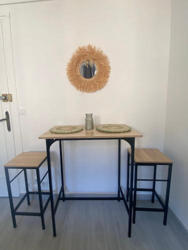 une table avec deux tabourets et un miroir sur le mur dans l'établissement Charmant appartement proche CDG, à Tremblay-en-France