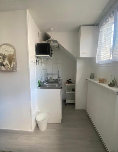 Il comprend une petite cuisine blanche avec un lavabo et des toilettes. dans l'établissement Charmant appartement proche CDG, à Tremblay-en-France