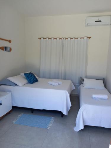 two beds in a room with white walls at Brisa Mar Suítes in Arraial d'Ajuda