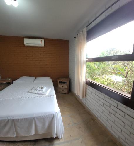 a bedroom with a white bed and a window at Recanto dos Passaros centro Penedo RJ in Penedo