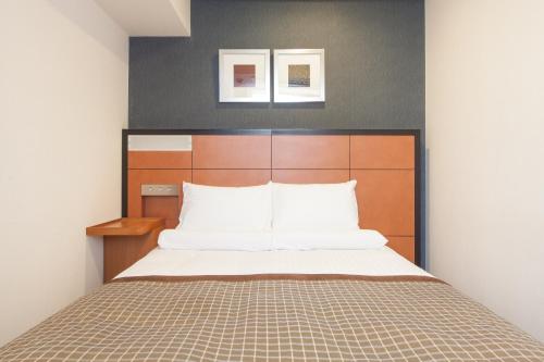 a bedroom with a bed with a wooden headboard at HOTEL MYSTAYS Sakaisuji Honmachi in Osaka