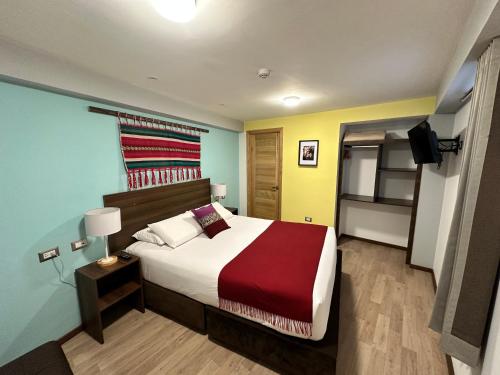a bedroom with a large bed with a red blanket at CASA CRISTOBAL Centenario in Cusco