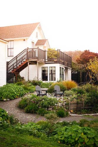 a house with a deck and two chairs in a garden at Nicholson House at Beaujolais in Mendocino