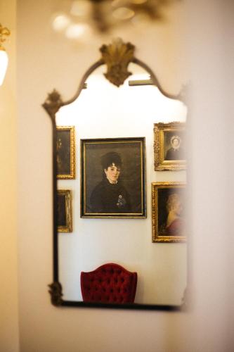 a mirror hanging on a wall with portraits on it at Nicholson House at Beaujolais in Mendocino