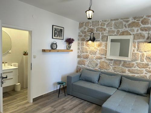 ein Wohnzimmer mit einer Couch und einer Steinwand in der Unterkunft Family friendly house with a swimming pool Mundanije, Rab - 23393 in Rab