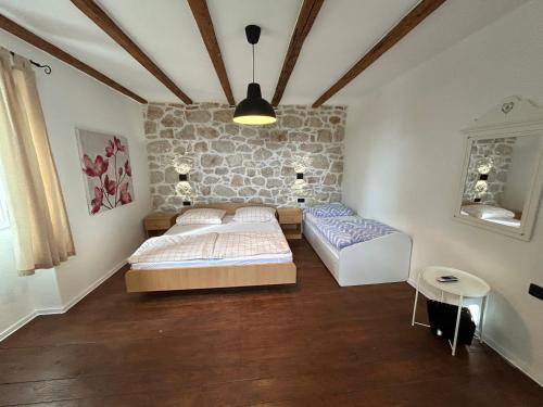 2 Betten in einem Zimmer mit einer Steinmauer in der Unterkunft Family friendly house with a swimming pool Mundanije, Rab - 23393 in Rab