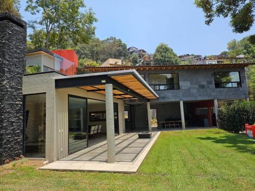 a house with a porch with a patio at Villa en el Bosque de Avándaro - Vista al Lago in Valle de Bravo