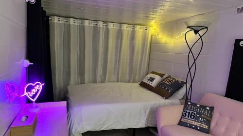 - une petite chambre avec un lit et une lumière violette dans l'établissement Duo indépendant, piscine et jacuzzi Espace pour vos toutous, à Vidauban