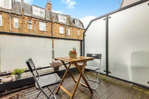 a balcony with a wooden table and two chairs at Omega Terrace, Luxury Modern Interior, Located Close To Alexandra Palace in London
