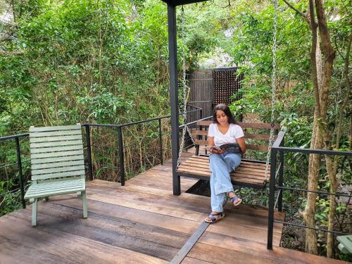 a woman sitting on a bench on a porch with a cat at The Backwaters Lodge in Wilpattu