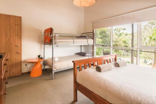 a bedroom with two bunk beds and a window at Coastal Cottage Bicheno in Bicheno