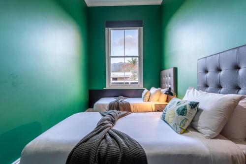 a green bedroom with two beds and a window at Tasman Holiday Parks - Coromandel in Coromandel Town