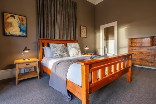 a bedroom with a wooden bed and a dresser at Tasman Holiday Parks - Coromandel in Coromandel Town