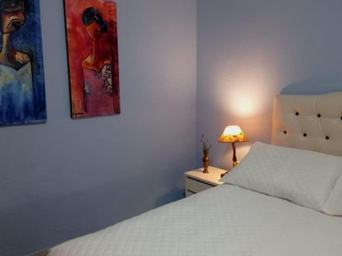 a bedroom with a bed and two paintings on the wall at El Arrayan " No acepta mascotas" in Tacuarembó