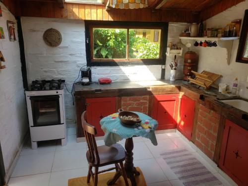 a small kitchen with red cabinets and a window at Sítio em Lumiar com piscina natural, sauna, churrasqueira e lareira in Nova Friburgo