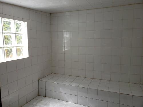 a white tiled shower with a window at Sítio em Lumiar com piscina natural, sauna, churrasqueira e lareira in Nova Friburgo