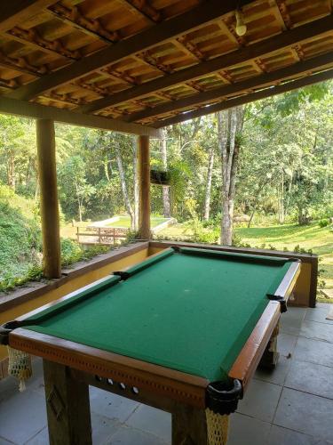 a pool table sitting under a pavilion in a yard at Sítio em Lumiar com piscina natural, sauna, churrasqueira e lareira in Nova Friburgo