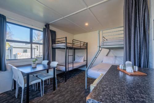 a room with bunk beds and a table and a table and chairs at Tasman Holiday Parks - Coromandel in Coromandel Town