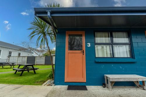 a blue house with a orange door and a picnic table at Tasman Holiday Parks - Coromandel in Coromandel Town
