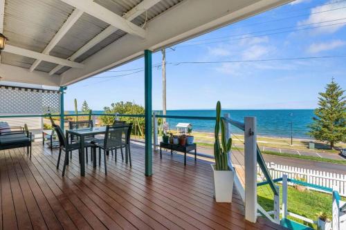 a deck with a table and chairs and the ocean at Kitesurfer in Scarborough