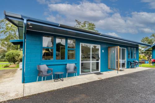 a blue building with two chairs and a table at Tasman Holiday Parks - Coromandel in Coromandel Town