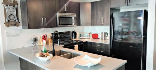a kitchen with a counter and a black refrigerator at Monki Di Executive Suites - Alura in Calgary