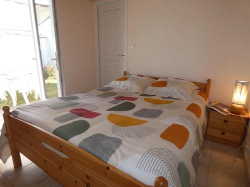 - un lit avec une couette colorée dans une chambre dans l'établissement Maison de vacances à Notre-Dame-de-Monts, proche plage, jardin, 6 pers, animaux permis - FR-1-540-283, à Notre-Dame-de-Monts