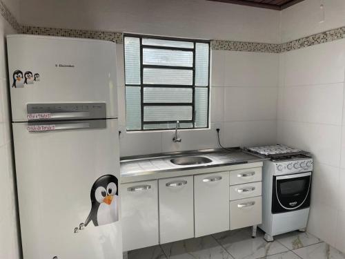 a small kitchen with a penguin on the refrigerator at J Morelli s - A 2 Minutos dos Melhores Parques de Olímpia in Olímpia
